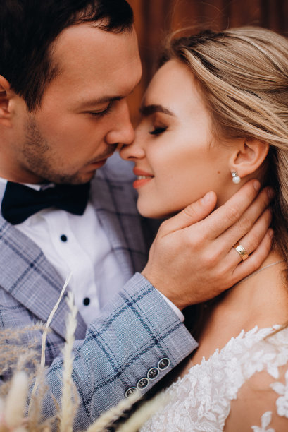 一对新婚夫妇在自然光下的肖像。身着优雅礼服的新郎闭上眼睛，温柔地拥抱美丽的新娘图片下载