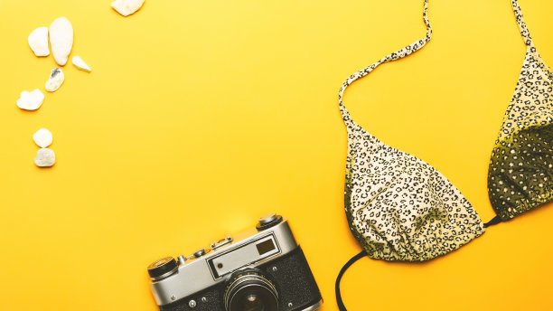 暑假旅游概念。旅游项目。海滩配件。泳衣，黄色背景的相机。本空间图片下载