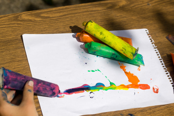 俯视图的孩子手和彩色水彩画在塑料管上的白纸背景，艺术和创意的概念。图片下载