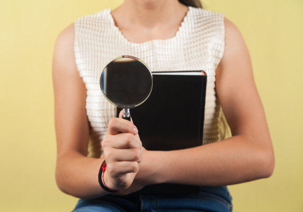 黄色背景上的女孩、书和放大镜。图片下载