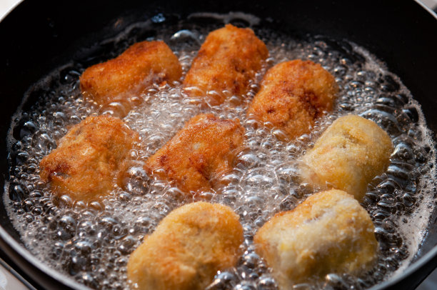 在装满食用油的平底锅中烹煮自制丸子并改变其颜色。厨房的一个场景。日本。图片下载
