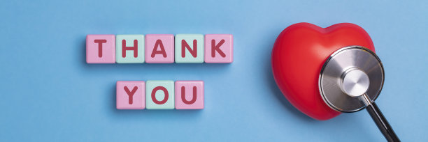 感谢词，医用听诊器和蓝色背景上的红心。玩具积木上的文字。图片下载