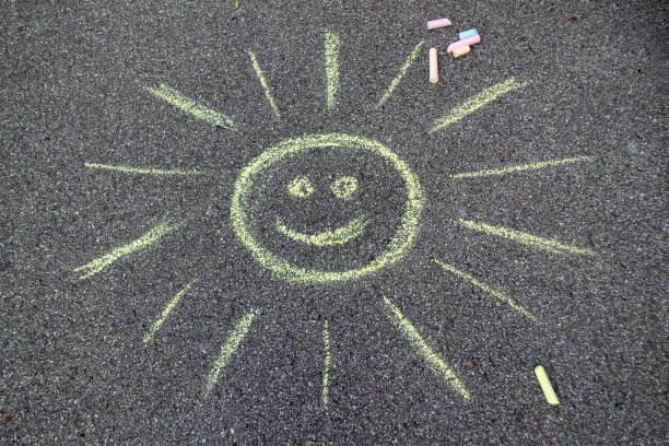 阳光洒在沥青上，用彩色粉笔作画。孩子们沉浸在阳光下的微笑中图片下载