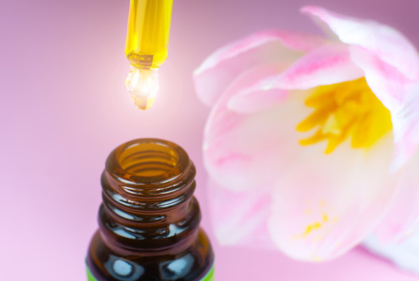 粉色郁金香靠近化妆品油瓶和移液管在粉红色的背景。闭上液滴滴落。美容、医药、保健理念。宏观照片。自然,生态化妆品。图片下载