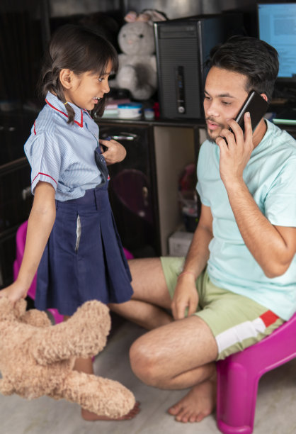 忙碌的印度父亲一边打电话一边准备女儿去上学。图片下载