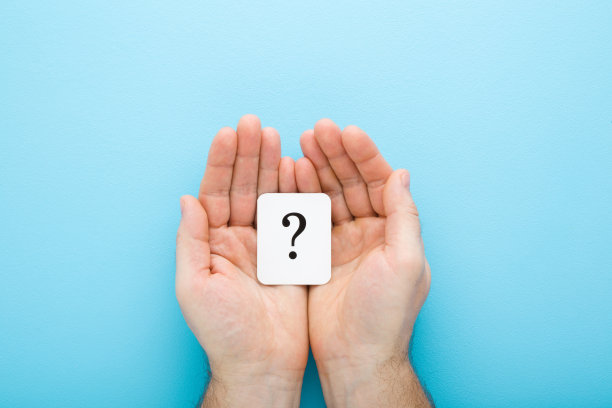 白色的问号卡片在年轻人的手掌上浅蓝色的桌子背景。柔和的颜色。视角拍摄。做决定的计划、想法或其他想法的概念。自顶向下的观点。图片下载