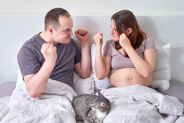 一个丈夫和一个怀孕的妻子在他们家的床上争吵。一对夫妇在怀孕期间的争斗和攻击图片下载