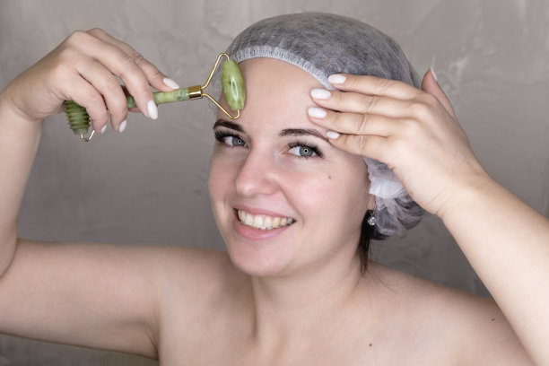 女人在用按摩轮做面部按摩。图片下载