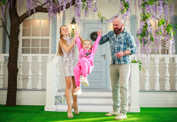 年轻的家庭和他们的女儿在院子里玩开花植物的乐趣图片下载