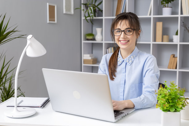 一个快乐的年轻女性自由职业者在家用笔记本电脑工作的肖像。女学生在家远程学习。图片下载