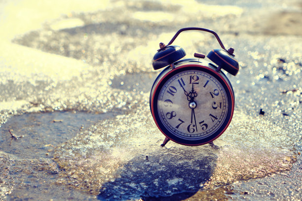 古老复古的闹钟在春天融化的雪上。图片下载