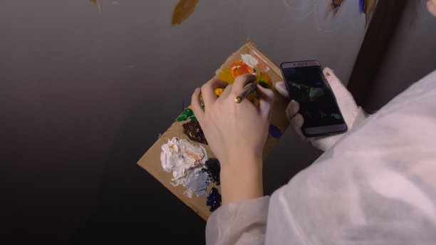 艺术家设计师在墙上画了一只鹰。工匠装饰师用丙烯酸油彩在电话里看素描画。黑暗的魔幻电影。图片下载