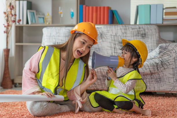 小亚洲女孩工程师戴着黄色的头盔，通过扩音器和她的母亲，教育和职业理念图片下载