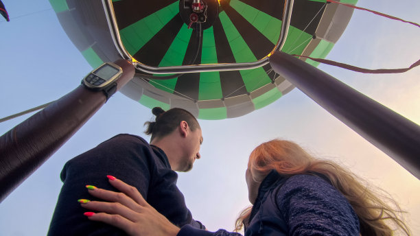 探险情侣在热气球上玩西瓜。男人和女人亲吻拥抱相爱。燃烧器引导火焰进入外壳。快乐的人。图片下载