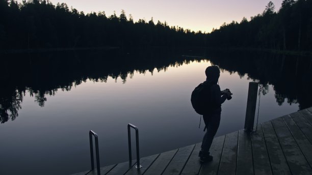 剪影旅行者拍摄风景在森林，河流。木材码头。一个女人拍了漂亮的黑魔法夜景。女孩用相机拍照。图片下载