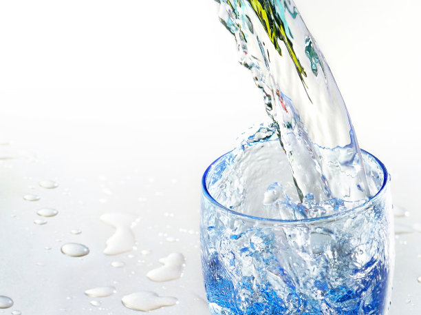 一股干净透明的冷水倒进银白色背景的蓝色玻璃烧杯里。图片下载