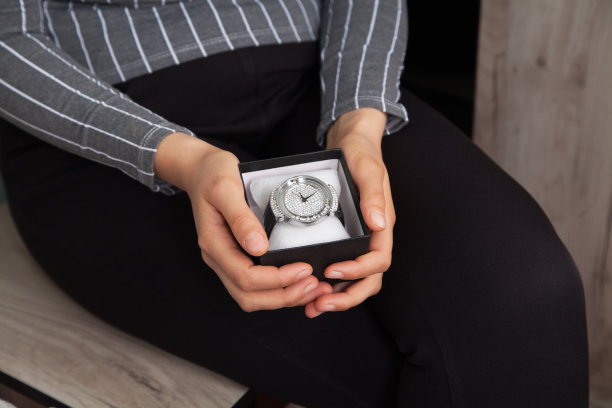 一个女人拿着一个装着漂亮女人手表的盒子。图片下载