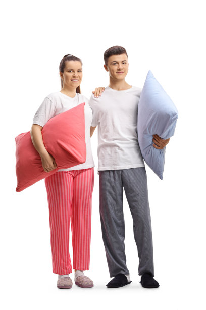 一个穿着睡衣抱着枕头的年轻男女的全身像图片下载