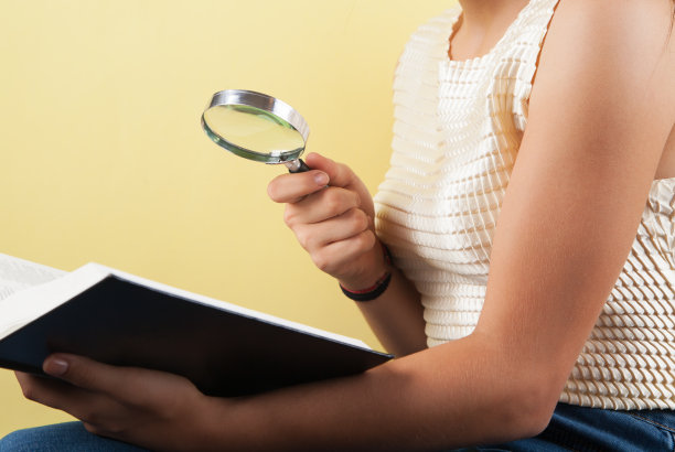 黄色背景上的女孩、书和放大镜。图片下载