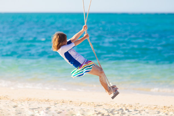 孩子在摇摆。孩子们在海滩上荡秋千。图片下载