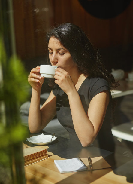 一个年轻美丽的女人坐在一个露天咖啡馆喝咖啡的肖像图片下载