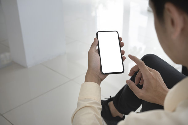 近肩视图的商人使用移动电话在办公室。图片下载