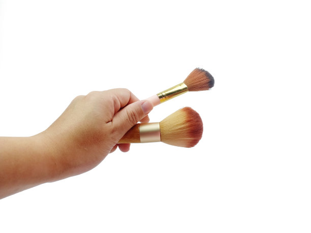 亚洲女人手握两化妆刷孤立在白色背景与剪切路径。化妆和美容概念。图片下载