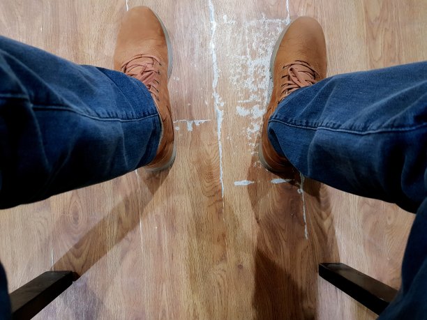 一个男人坐在椅子上，脚放在地板上的低部分。图片下载