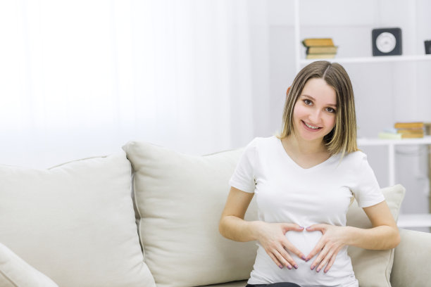 这是一张可爱孕妇的照片，她的手指放在肚子上，露出了一颗心。图片下载