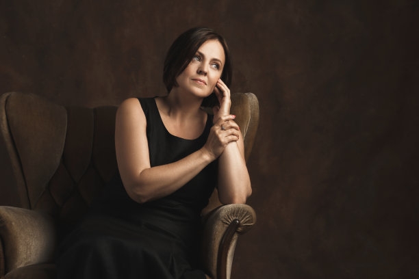 坐在棕色天鹅绒扶手椅上的美丽中年妇女图片下载