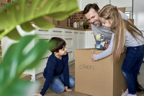 孩子们帮助他们的父亲为搬家打包纸板箱图片下载
