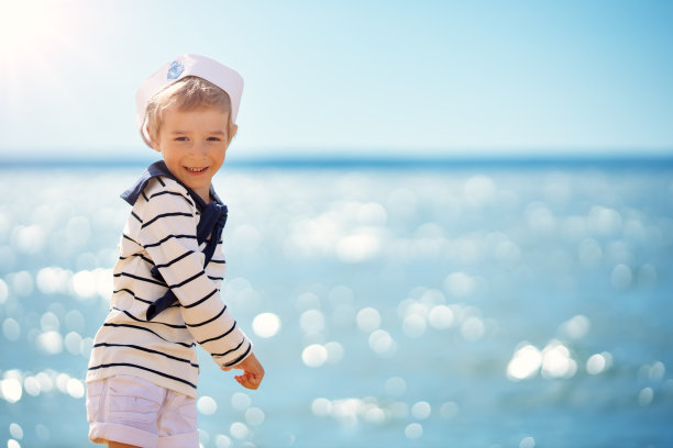 可爱的男孩戴着水手帽站在海边的大海图片下载
