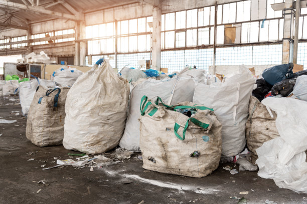 堆许多肮脏的大袋容器与用过的水宠物瓶收集回收和再用在废弃的回收工厂仓库。保护环境免受污染图片下载