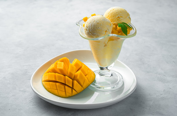 白色盘子上有冰淇淋和新鲜芒果的甜点图片下载