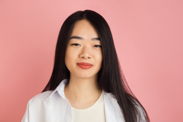 粉色画室背景上的亚洲年轻女子肖像。人的情感、面部表情、青春、销售、广告的概念。图片下载