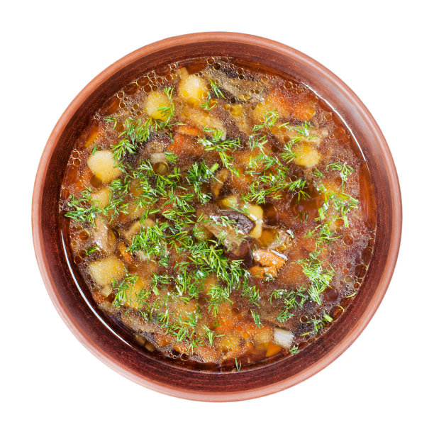 野生蘑菇蘑菇汤在一个棕色的粘土盘子和绿色孤立在白色的背景图片下载