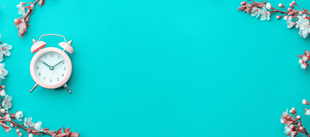 春天的边界，春天的花朵和四月的花卉自然与闹钟在蓝色的背景。枝头的杏花宏柔聚焦。复活节和春天的贺卡，拷贝空间。春天。图片下载