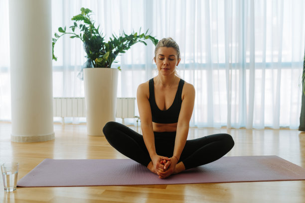 正面照片集中年轻女子在束缚角瑜伽姿势。年轻女子自我隔离在家锻炼。图片下载