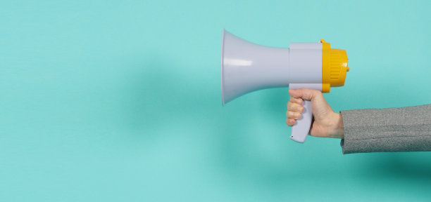 手持扩音器，身穿灰色套装，背景为绿色或薄荷色或蒂凡尼蓝色。图片下载