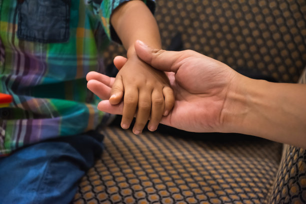 父亲的手牵着一个小孩的手。图片下载