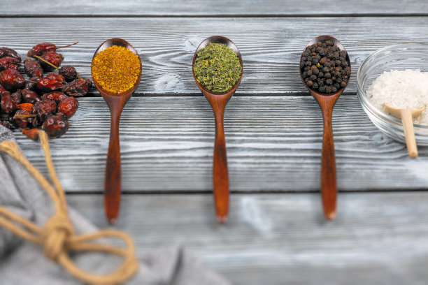 质朴的木桌上放着几勺各种香料。前视图。烹饪美味菜肴的概念。图片下载