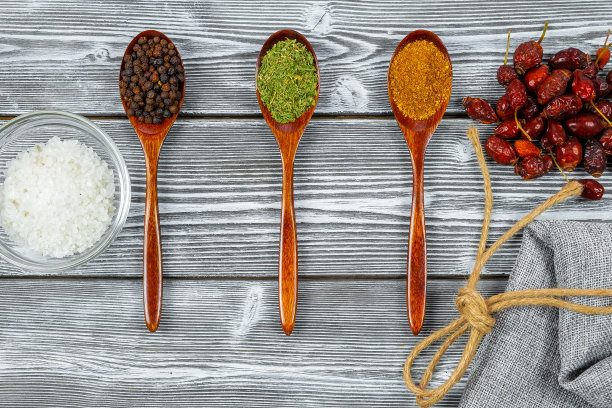 质朴的木桌上放着几勺各种香料。前视图。烹饪美味菜肴的概念。图片下载