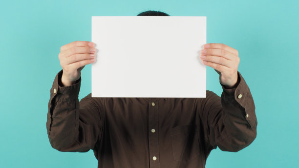 空白的A4纸。空白板在男人的手和穿海军蓝衬衫在绿色薄荷或蒂芙尼蓝色背景。图片下载