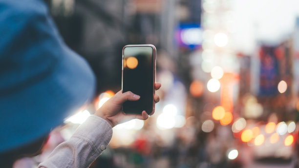 在户外手持智能手机进行在线数字应用的女人。图片下载