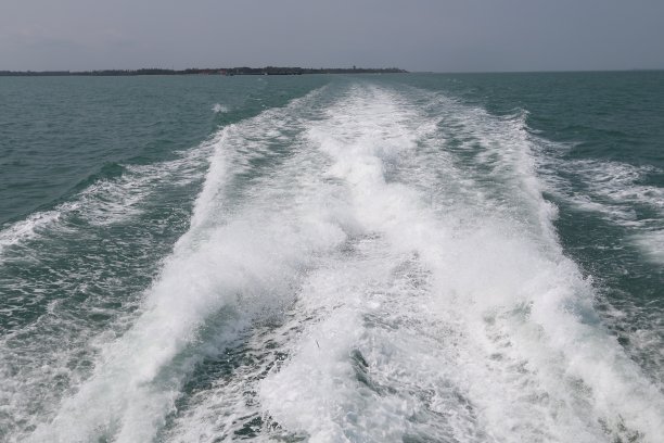 海上有船的尾流。快艇尾部的鸟鸣掠过海面。清澈湛蓝的海面上，小船后面的波浪图片下载