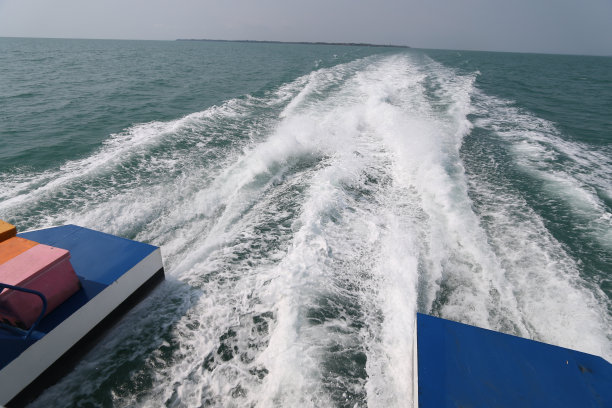 海上有船的尾流。快艇尾部的鸟鸣掠过海面。清澈湛蓝的海面上，小船后面的波浪图片下载