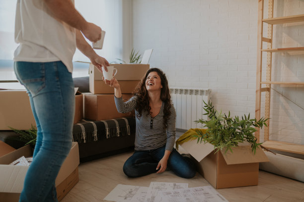 这张照片是一个快乐的年轻女人在搬家那天打开箱子，准备喝咖啡的休息时间。一个年轻人刚刚为他和他的妻子煮了一杯咖啡。图片下载