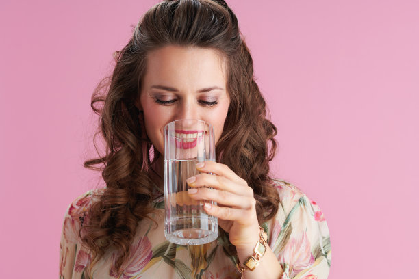 微笑时髦的女人与长波浪浅棕色的头发在粉红色图片下载