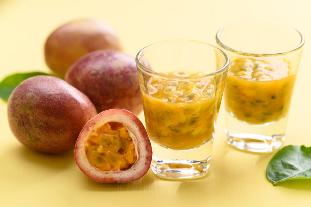 新鲜的百香果汁在玻璃上的黄色背景图片下载