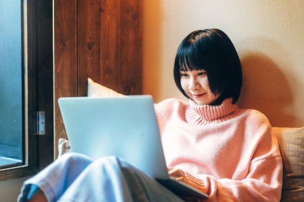 年轻的亚洲成年妇女使用笔记本电脑在床上工作。图片下载